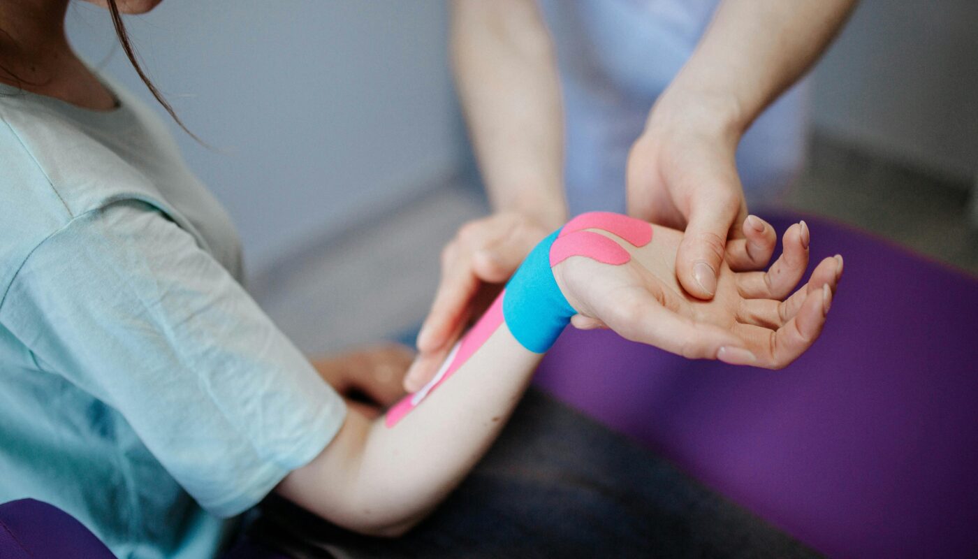 Photo by Danik Prihodko: https://www.pexels.com/photo/person-applying-kinesio-tape-on-a-girl-s-arm-and-wrist-8219158/