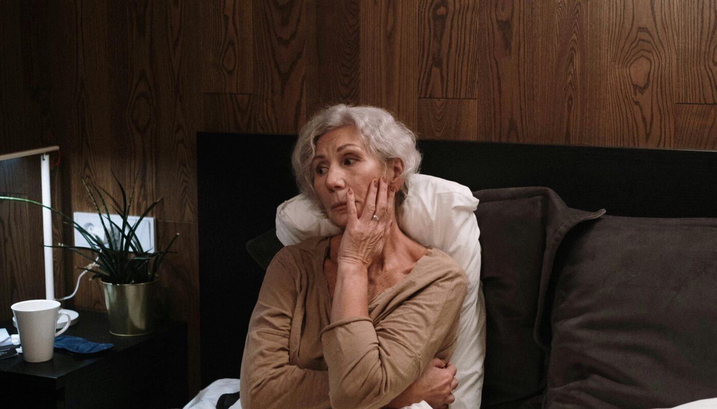 Photo by Ron Lach : https://www.pexels.com/photo/woman-sitting-on-a-bed-touching-her-face-8527643/