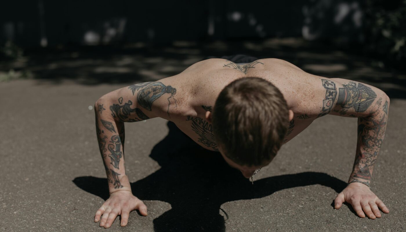 Photo by cottonbro studio: https://www.pexels.com/photo/a-shirtless-tattooed-man-doing-push-ups-on-the-concrete-floor-5320032/