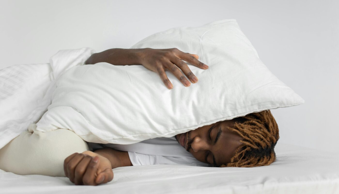 Photo by KATRIN BOLOVTSOVA: https://www.pexels.com/photo/man-sleeping-with-pillow-on-his-head-7445324/